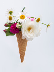 Ice cream waffle cone with a bouquet of summer flowers of roses and daisies. Diet and thinking outside the box design concept