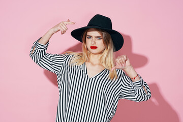 glamorous woman in black hat and striped shirt bright makeup pink background