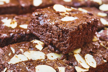 pieces of fresh homemade chocolate brownie, square shape, with sliced almond on top, close up