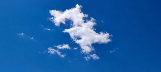 A whimsical white cloud. Not a dark blue saturated background of the sky, a lonely cloud of a bizarre shape with right angles and lines floats. The cloud resembles the number 3 or the letter Z.