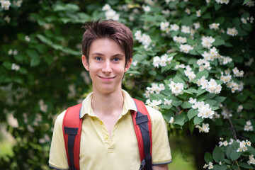 Young handsome 15 years old teen boy wearing yellow t-shirt with backpack looking at camera and...