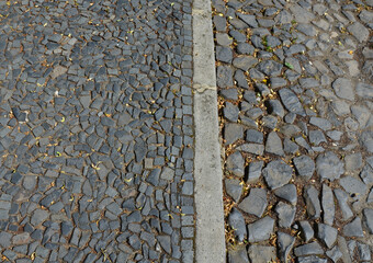 sidewalk of volcanic stones of gray shiny color. For years, the surface of the paving is polished....