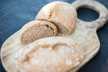 Homebaked hot appetizing bread with crispy crust sliced on wooden cutting board