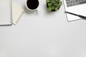 White desk  with Laptop, blank notepad, flower, coffee cup and pen. Flat lay top view copy space.