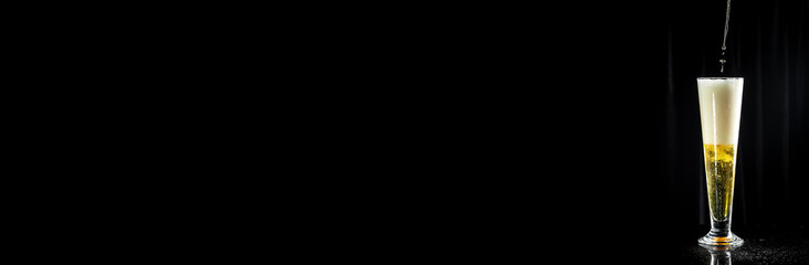 Cold glass filled with beer. splash, black background. Long banner format