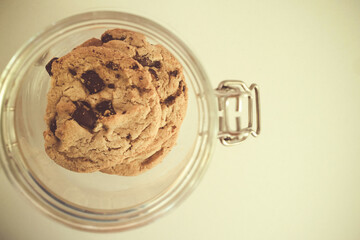 top view of homemade delicious chocolate chip cookies in the glass jar ready for easy morning meal or a snack for coffee with copy space, selective focus. vintage photo and film style.