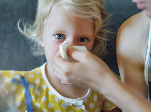 Parent hand helping the little girl to blow her nose with a hygienic wet wipe. Seasonal sickness. 