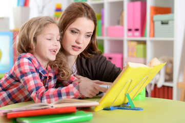 Cute little girl with her mother doing homework