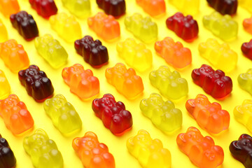 Delicious gummy bear candies on yellow background, closeup