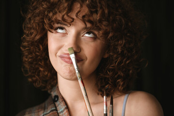 Obraz premium Smiling young redhead woman in plaid shirt