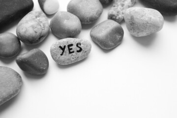 Pebble stone with the text yes on the table in a heap of pebbles