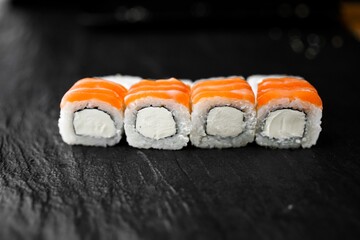 Japanese sushi roll philadelphia on black stone. Sushi with rise, cheese and salmon.