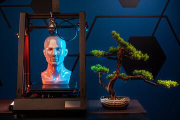3d printer at work on a bonsai tree table. 3d printer prints head, advertising photo blue and...