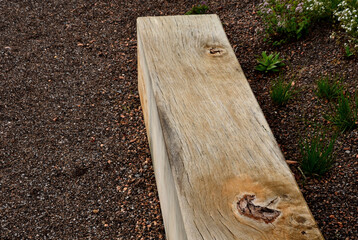 a wooden oak prism serves as a bench in the garden. for better drying of the wood, grooves are...