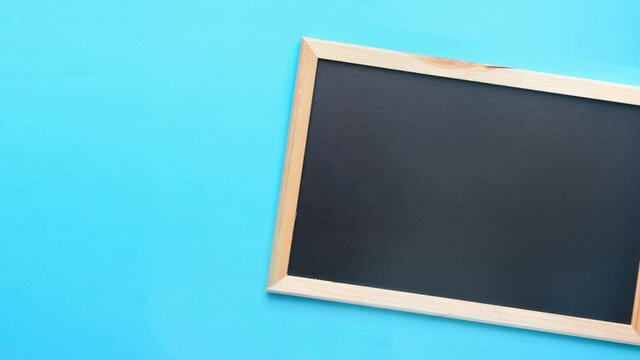 Stop motion animation footage of blank Mock Up of Black Chalkboard on Blue Background. Back to School Concept Education Learning. Creative cartoon