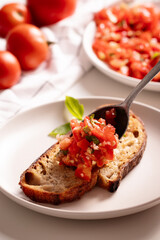 Cutting fresh tomato and preparng homemade bruschetta with olive oil, garlic and basil