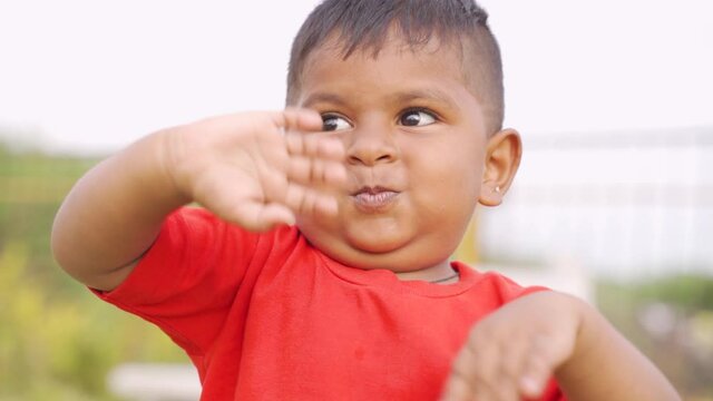 Happy Cute little boy waving hands by loking at camera at park - concept of playful, say hai and excited children.