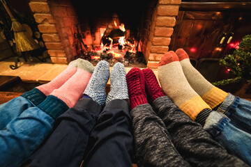 Legs view of happy family wearing warm socks in front of fireplace during Christmas day - Focus on...