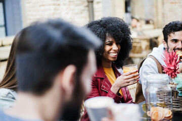 Fototapeta na wymiar Happy multiracial friends eating and drinking outdoor at vintage bar restaurant - Main focus african girl face