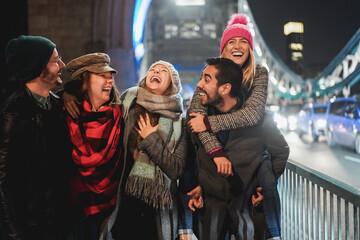 Fototapeta na wymiar Happy friends having fun walking around the city in winter night - Focus on center girl face