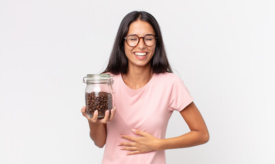 young hispanic woman laughing out loud at some hilarious joke and holding a coffee beans bottle