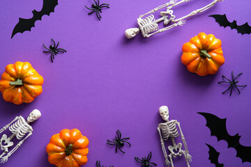 Frame of Halloween decorations on purple background. Flat lay skeletons, bats silhouettes, spiders, pumpkins. Happy Halloween concept.