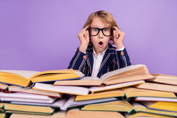 Portrait of attractive funny amazed cheery boy reading stack book pout lips isolated over purple violet color background