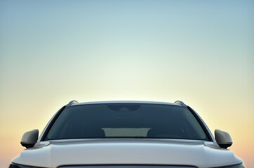 Obraz na płótnie Canvas top front part of white parked car against dusk sky