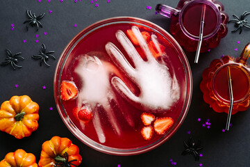 Halloween party concept. Bowl with bloody drink, frozen hands, strawberries and halloween...