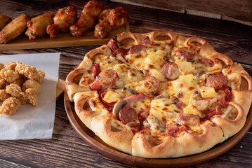 Delicious Italian pizza as mighty meat (Ham, Smoked Sausage, Pepperoni, Mushroom, Pineapple on top) on wooden background
