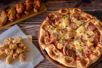 Italian fresh pizza as meat deluxe (meat and pineapple) for dinner on wooden table