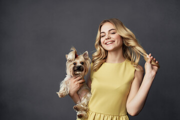 woman in a yellow dress with a small purebred dog in the hands of fun fashion