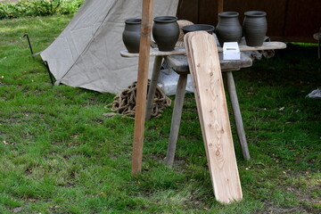 Close up on equipment of a medieval potter with a straw hat laying on a wooden table next to some...