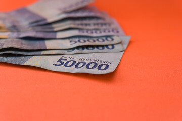Obraz premium The Indonesian currency is rupiah, which is very much scattered and is worth fifty hundred thousand rupiah. Isolated in orange. For illustrations of news with the theme of economy, buying sell.