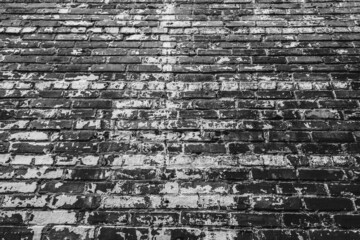 Old white paint and rough brick wall with receding perspective in black and white