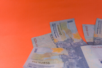 Obraz premium The Indonesian currency is rupiah, which is very much scattered and is worth fifty hundred thousand rupiah. Isolated in orange. For illustrations of news with the theme of economy, buying sell.
