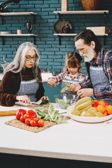 Senior grandparents couple with dgranddaughter cooking in kitchen