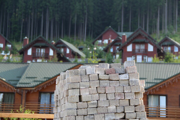 Pile Of Square Construction Bricks In Front Of Wooden Houses
