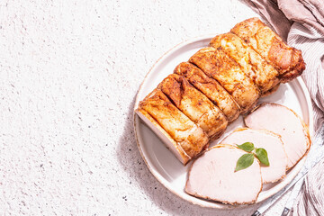 Baked pork loin on a ceramic stand with cutlery