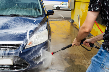 a man washes the car at the car wash. machine wash with water pressure