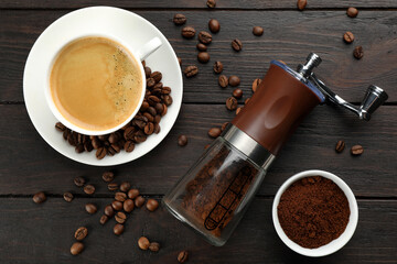 Modern manual coffee grinder with powder, beans and cup of aromatic drink on wooden table, flat lay