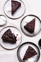 Slices of rich moist chocolate cherry cake. Homemade dark chocolate sweet brownies cakes with ice cream on greige linen tablecloth. Selective focus - 450319556