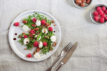 Summer salad with arugula, raspberries, mozzarella cheese and pecan nuts. Morning, breakfast, healthy food. Selective focus