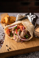 doner kebab, a shawarma in a pit of fresh vegetables and meat. with large spices. restaurant serving. on a dark background. for menus and ads