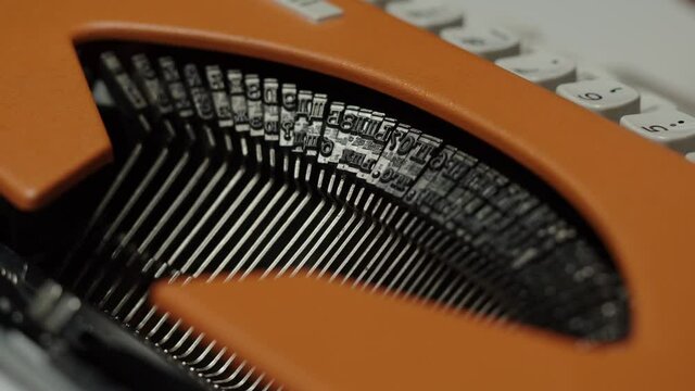 Human hands typing on retro typewriter close-up, fingers pressing buttons of old-fashioned typewriter keyboard on black background.