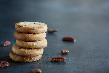 Stack of pecan sandies cookies stacked on a dark table. Selective focus with blurred foreground and background.