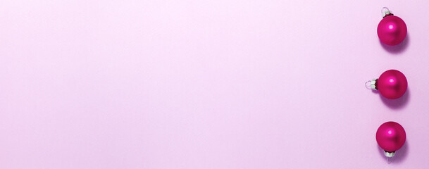 Pink Christmas balls on purple background on right side. Flat lay top view with copy space. Holidays concept