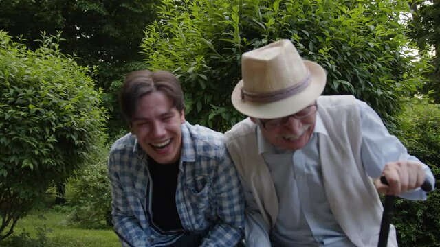 Grandfather and grandson tell very funny stories in a video chat and laugh sincerely