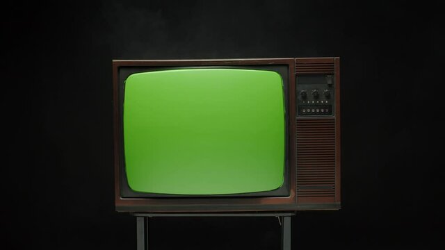 Old retro-style television with green sccreen on black background. Close-up of old-fashioned TV, cinematography concept.