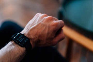 Selective focus shot of a male's hand wearing a black smart watch